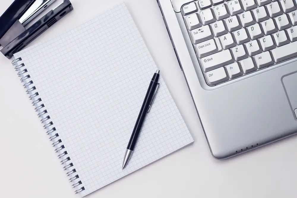 Arbeitsplatz mit Notizblock, Stift und Laptop